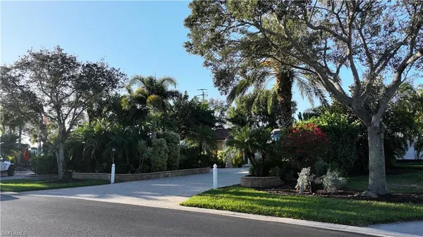 a front view of a house with a garden and trees