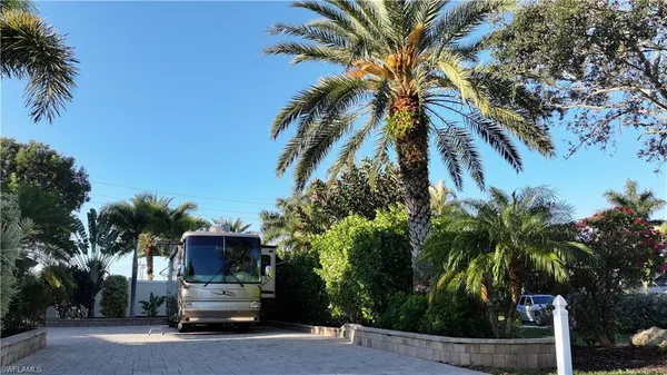 a view of car parked in front of house with palm trees