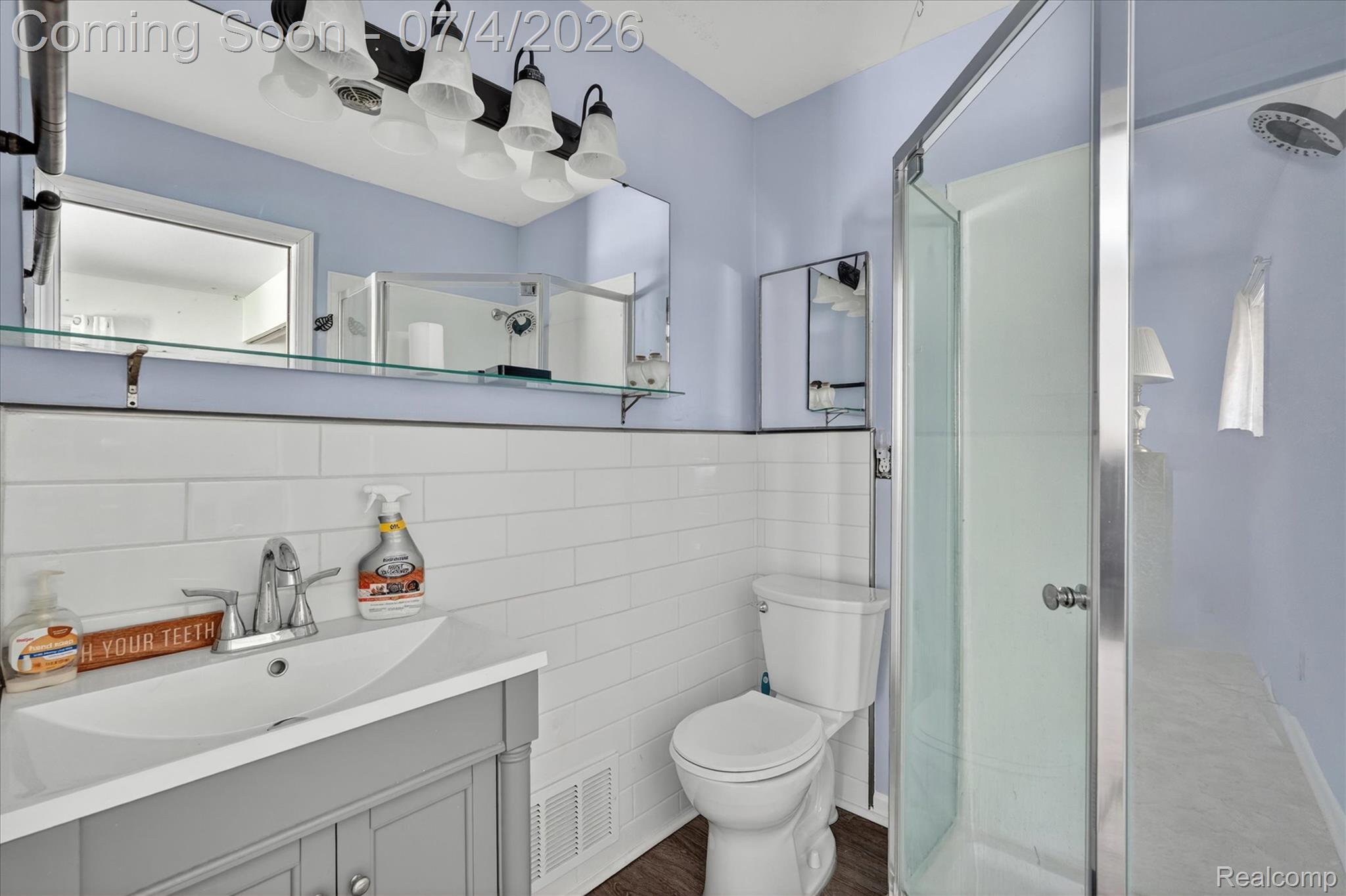 2091 North Irish Road Davison, MI 48423 - Photo 15 of 25 Bathroom featuring wood-finish flooring, a white subway tile wainscoting, and a single vanity with a white countertop and basin sink