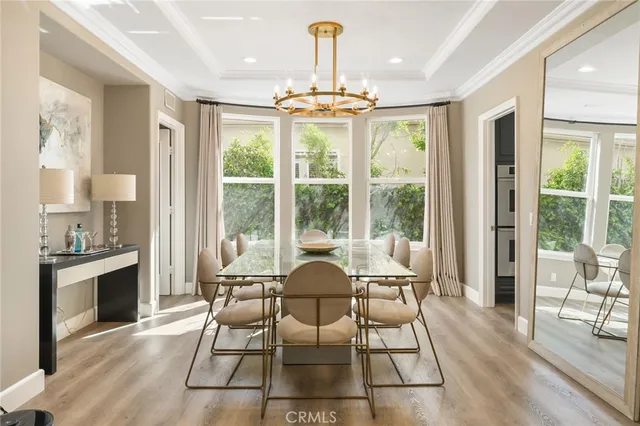 a dining room with wooden floor a chandelier a glass table and chairs