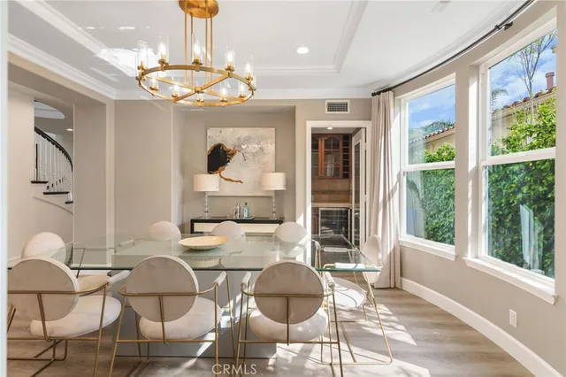 a dining room with wooden floor a chandelier a glass table and chairs