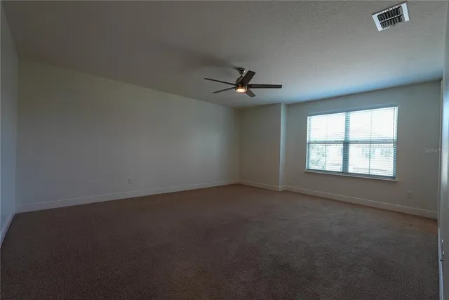 an empty room with windows and fan
