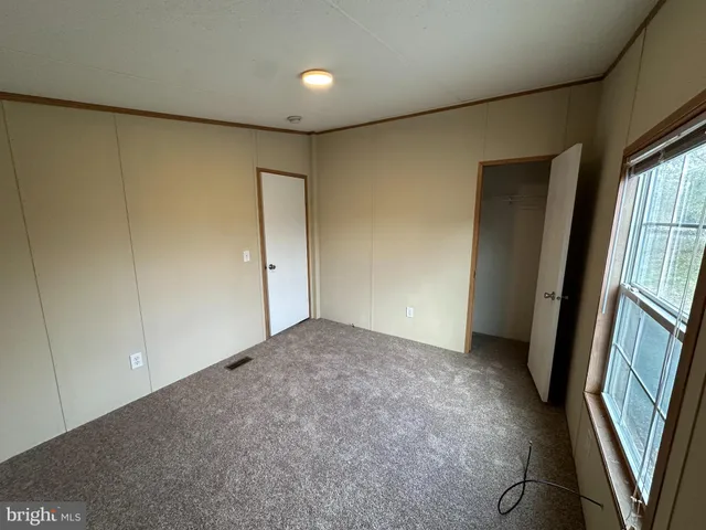 an empty room with closet and a hallway