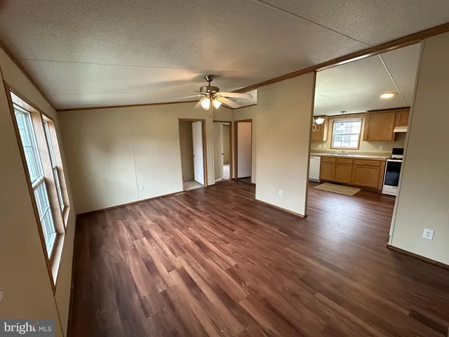 a view of an empty room and a kitchen
