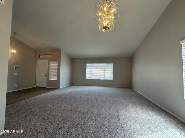 an empty room with a window and chandelier fan