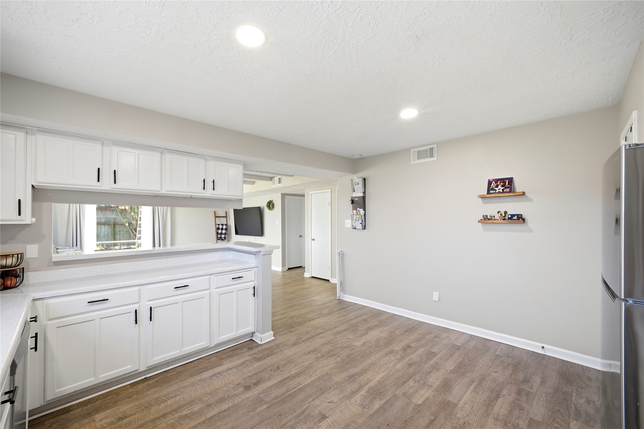 4718 Temple Bell Drive Spring, TX 77388 - Photo 22 of 50 Bright kitchen with white cabinets, modern appliances, and wood flooring. Open layout with ample lighting and a cozy, inviting atmosphere.