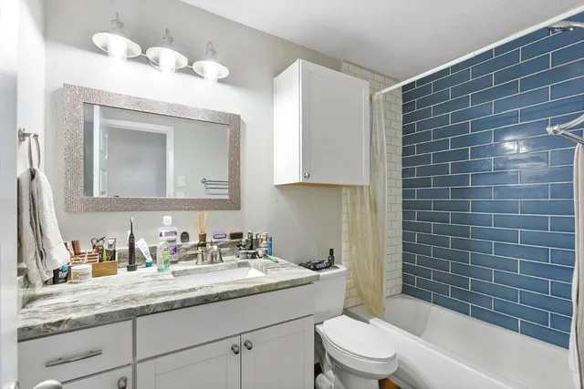 a bathroom with a granite countertop sink a toilet mirror and bathtub