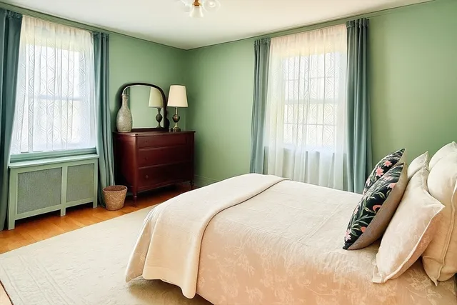 a bedroom with a bed and a dresser next to a window