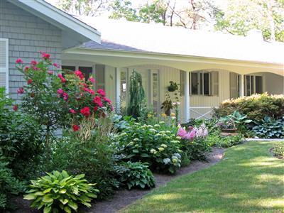 111 Goose Point Road Centerville, MA 02601 - Photo 5 of 21 a view of a white house with a flower garden and flower plants