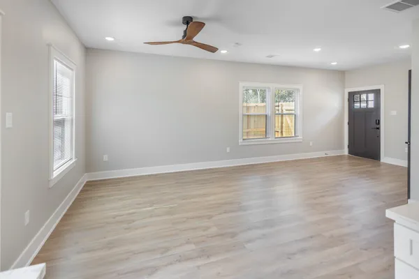 an empty room with wooden floor and windows