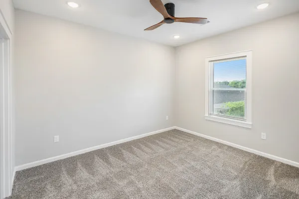 an empty room with a window and a fan