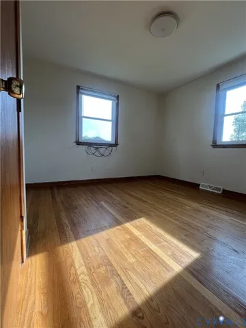 an empty room with wooden floor windows and closet