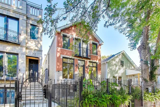 a view of a brick house with large windows and a tree