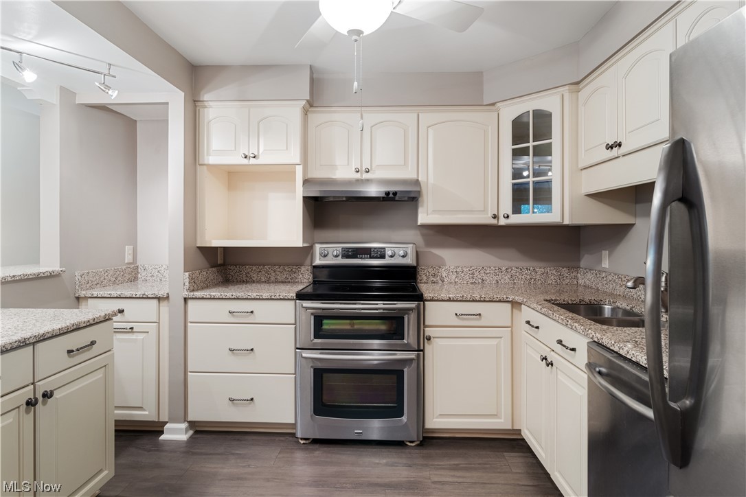 22555 Center Ridge Road, Unit 303 Rocky River, OH 44116 - Photo 7 of 33 Kitchen featuring appliances with stainless steel finishes, rail lighting, white cabinets, light stone counters, and dark hardwood flooring