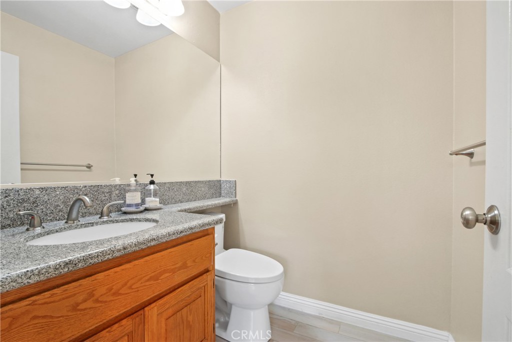 9221 Belcaro Drive Huntington Beach, CA 92646 - Photo 10 of 22 a bathroom with a granite countertop sink a toilet and a mirror