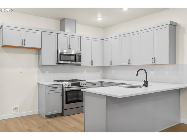 a kitchen with stainless steel appliances granite countertop a sink a stove and cabinets