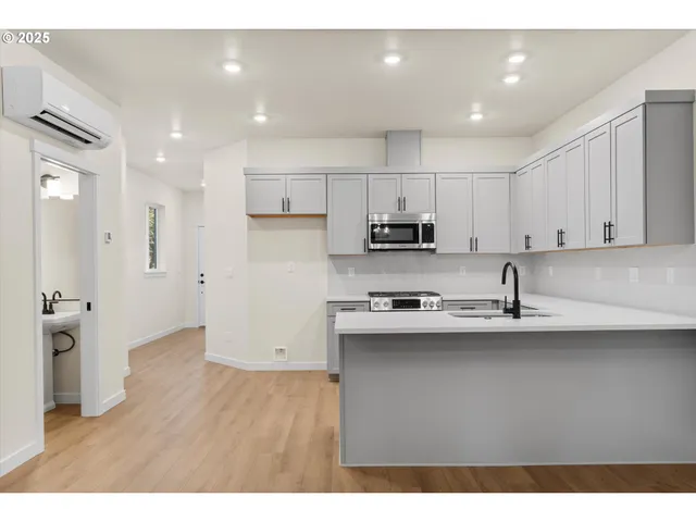 a kitchen with stainless steel appliances granite countertop a sink a stove a refrigerator and white cabinets