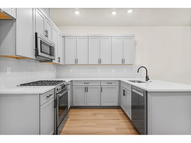a kitchen with stainless steel appliances granite countertop a sink stove and microwave