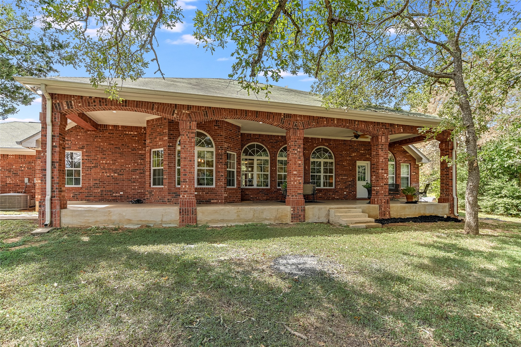 741 Knobbs Road McDade, TX 78650 - Photo 24 of 38 Brick veranda with graceful archways and a serene, tree-shaded backyard provides an inviting outdoor retreat.