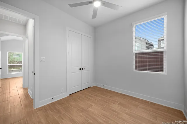 an empty room with wooden floor chandelier and windows
