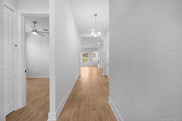 a view of a hallway with wooden floor and a bathroom