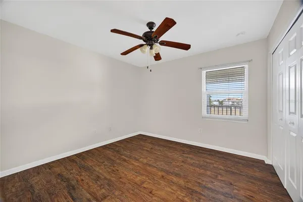 a view of a big room with wooden floor a ceiling fan and windows