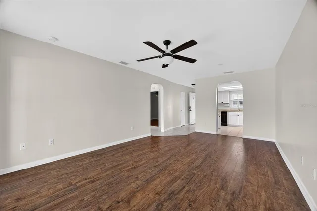 a view of empty room with wooden floor and ceiling fan