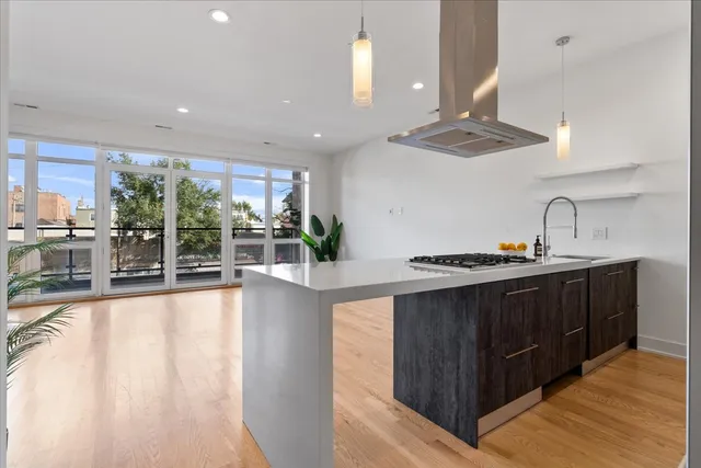 a large kitchen with stainless steel appliances a large counter top a stove a chimney a sink and a large window