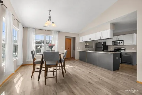 a kitchen with stainless steel appliances wooden floor dining table and chairs