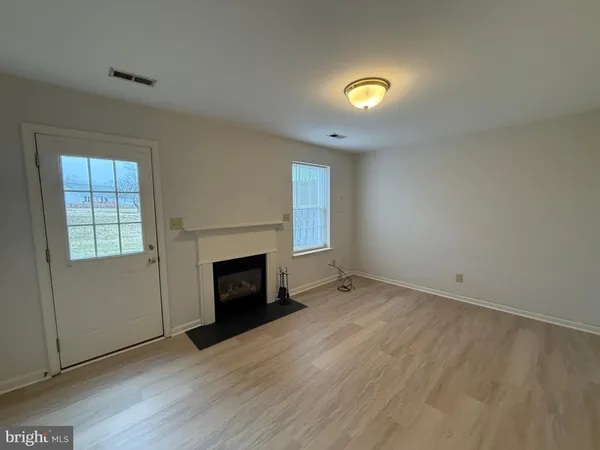 an empty room with wooden floor fireplace and windows