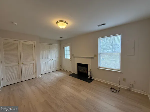 an empty room with windows a fireplace and wooden floor