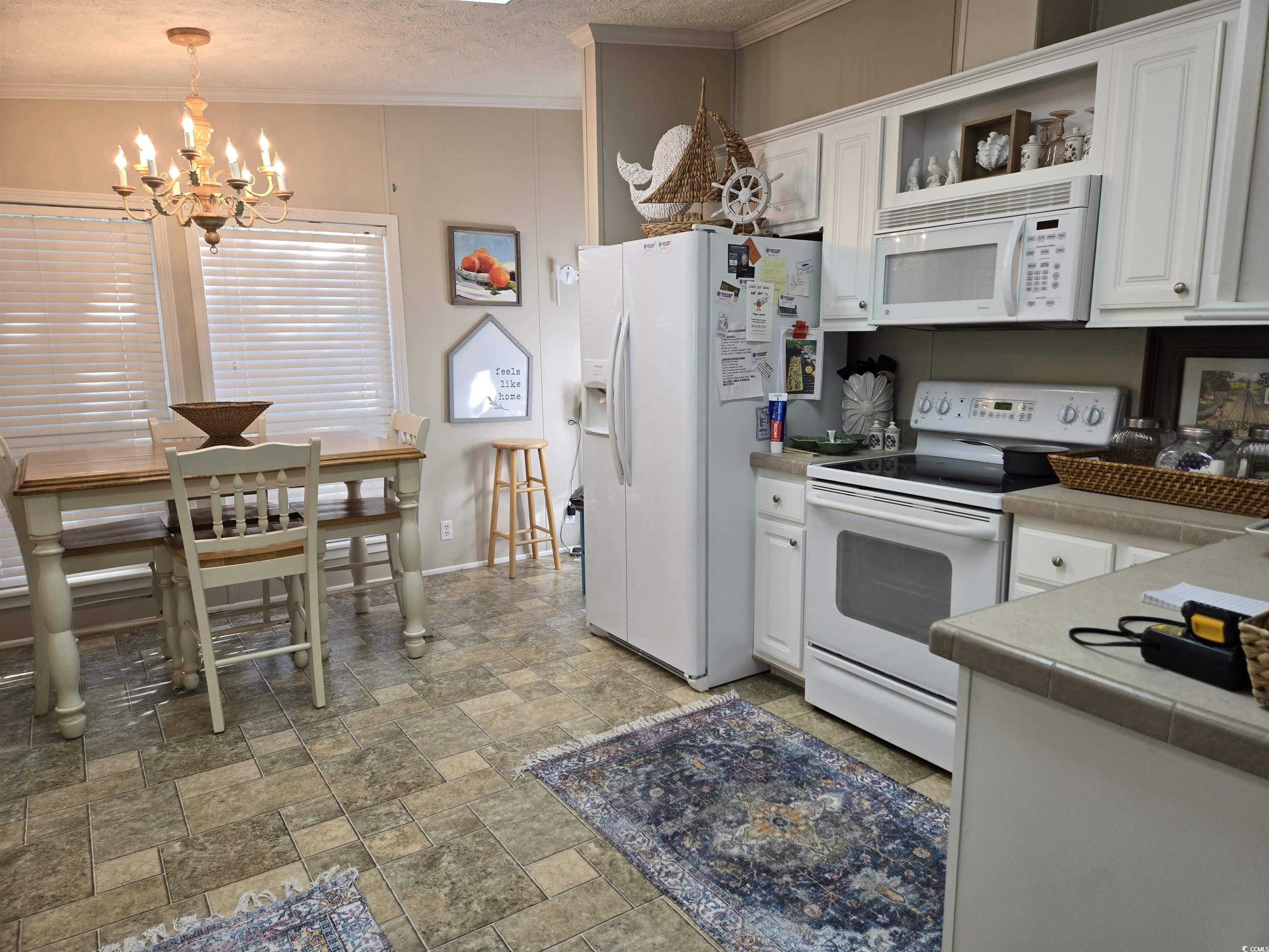 310 Clam Shell Circle Murrells Inlet, SC 29576 - Photo 14 of 32 Kitchen featuring white appliances, a chandelier, white cabinetry, crown molding, and light stone finish floors