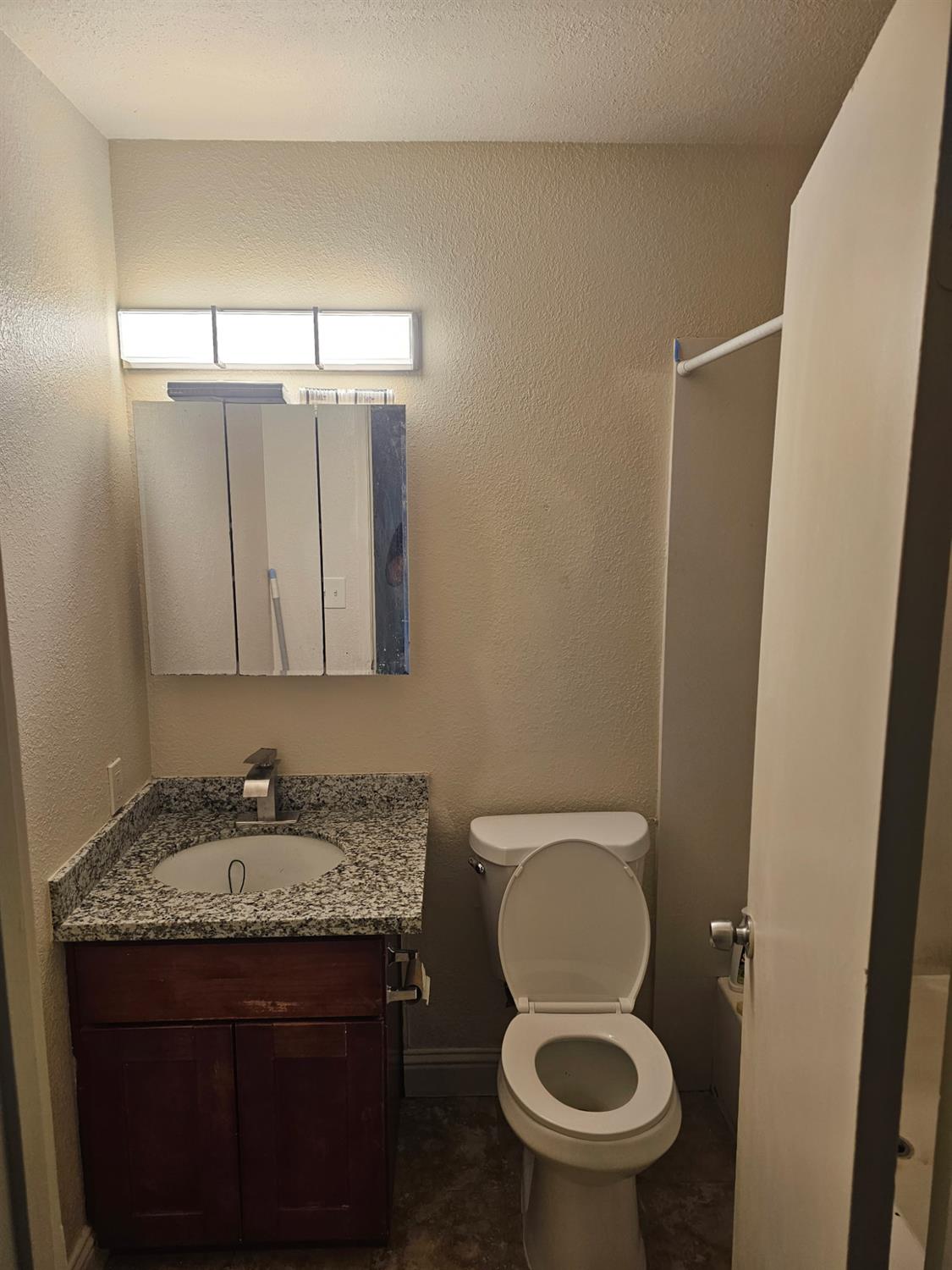 5830 Walerga Road, Unit 2 Sacramento, CA 95842 - Photo 6 of 8 a bathroom with a granite countertop toilet sink and mirror