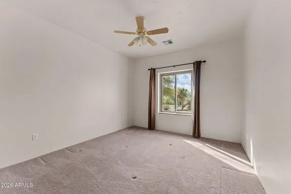 an empty room with windows and fan