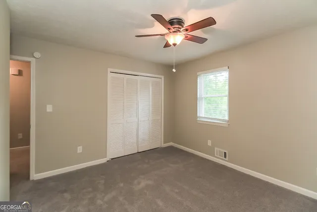 an empty room with a chandelier fan and windows