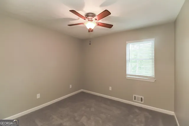 an empty room with window and ceiling fan