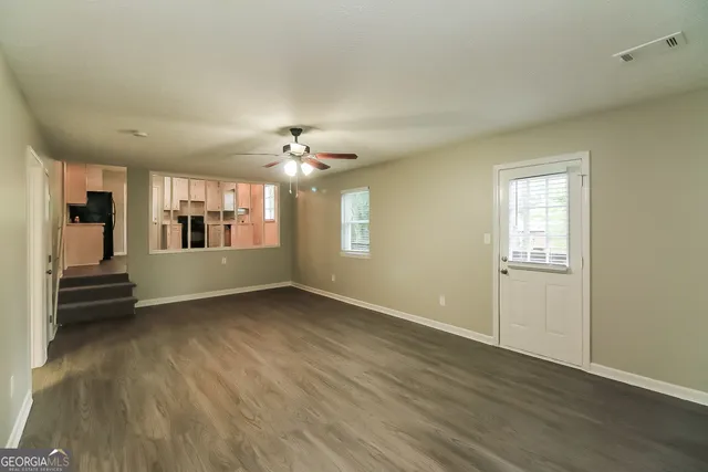 a view of an empty room with wooden floor and a window