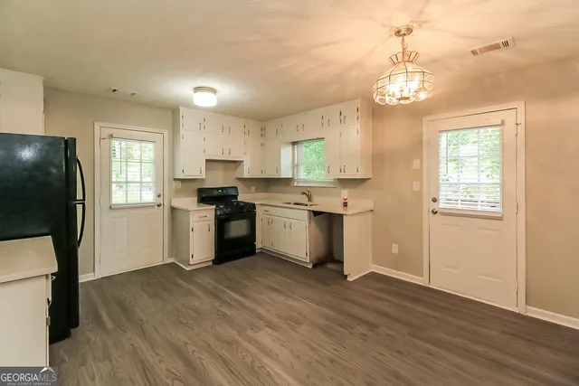 a kitchen with granite countertop wooden floors stainless steel appliances and window