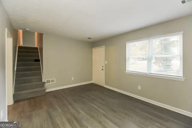 a view of an empty room with a window and wooden floor