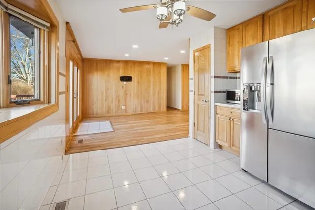 a view of a refrigerator in kitchen and an empty room with wooden floor