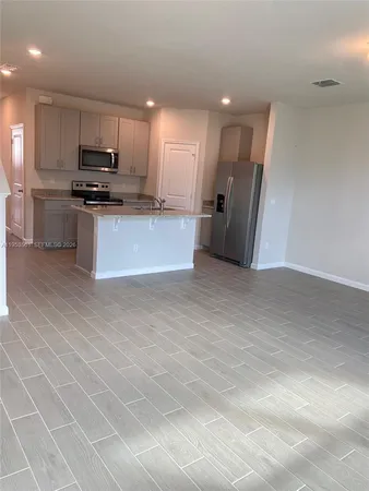 a kitchen with stainless steel appliances granite countertop a refrigerator stove top oven and cabinets