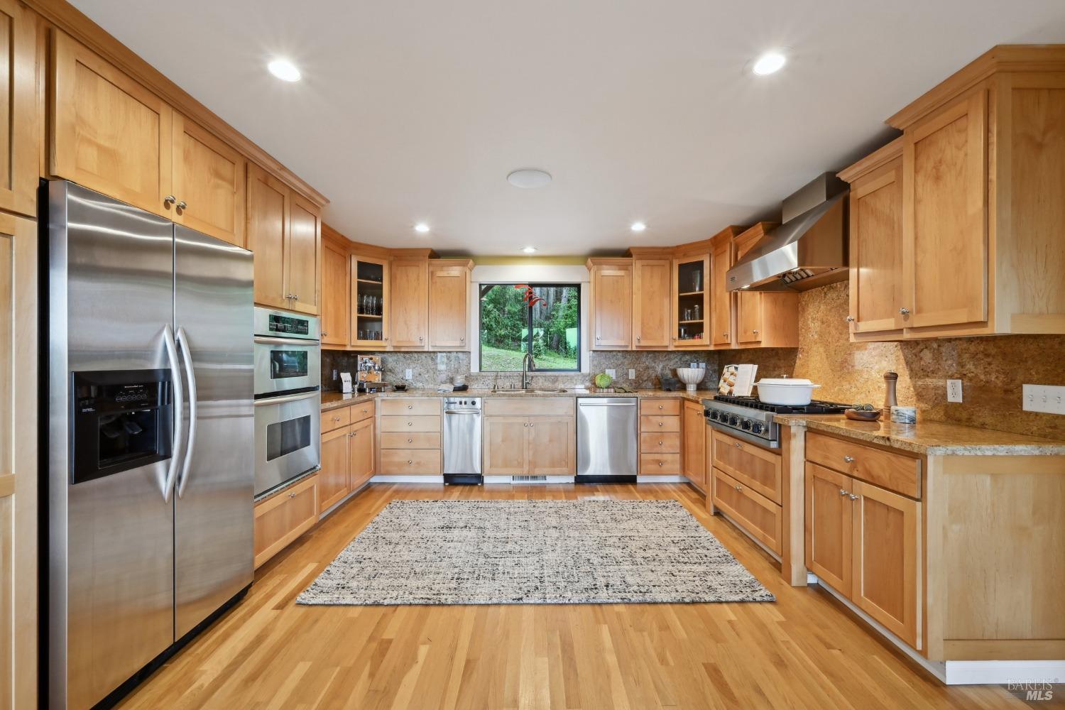 16495 Burl Lane Occidental, CA 95465 - Photo 12 of 31 a large kitchen with stainless steel appliances granite countertop a stove a sink dishwasher a refrigerator and white cabinets with wooden floor