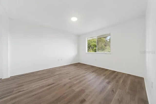 an empty room with wooden floor and window