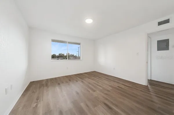 an empty room with wooden floor and windows