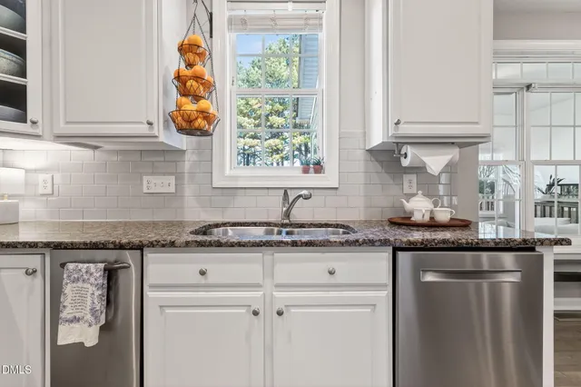 a kitchen with granite countertop white cabinets and a sink