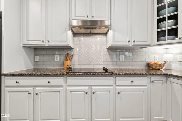 a kitchen with granite countertop white cabinets white appliances a sink and a window