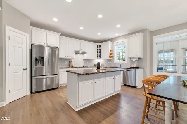 a kitchen with stainless steel appliances a table chairs refrigerator microwave and stove