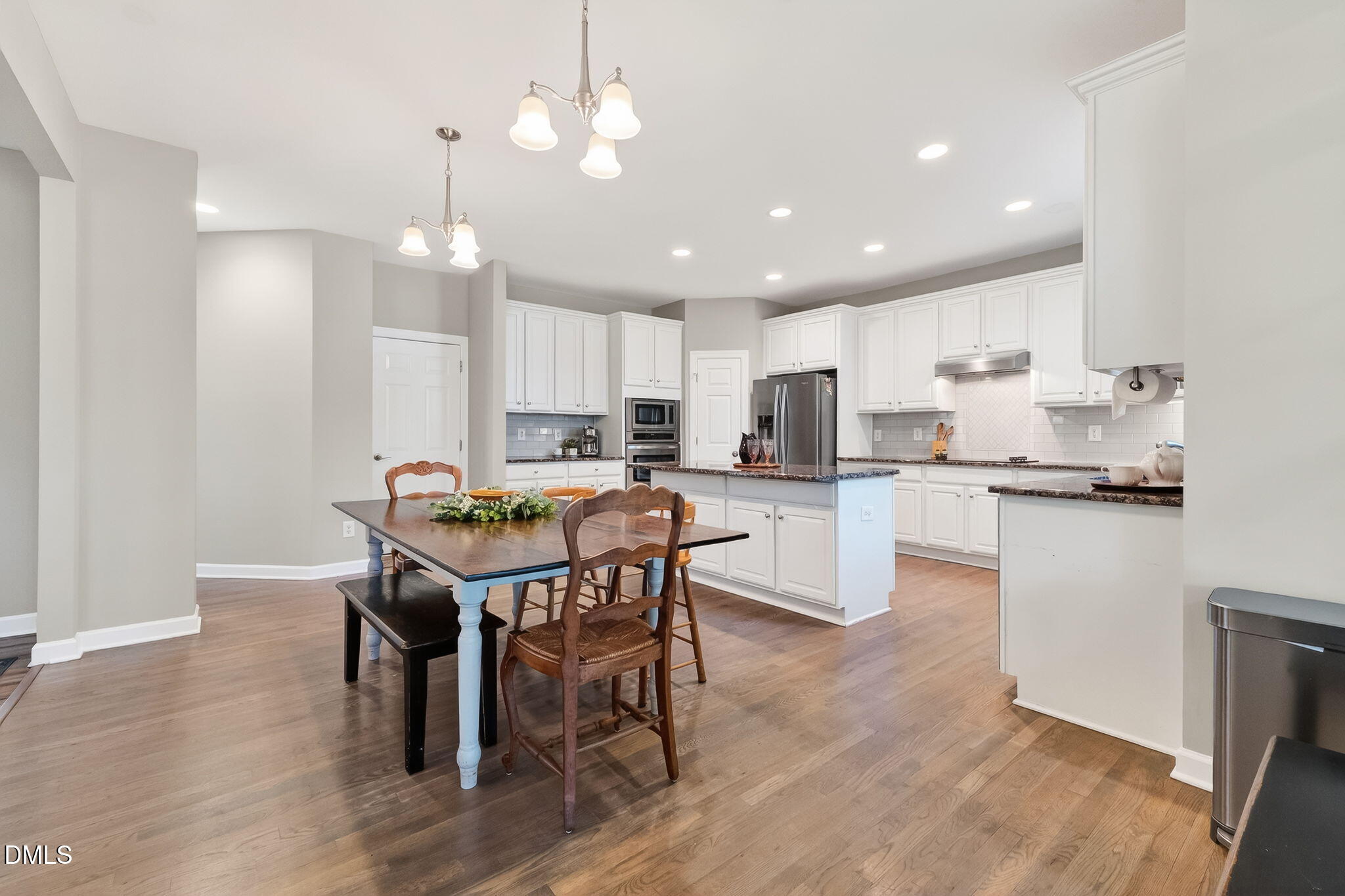 625 Toledo Court Rolesville, NC 27571 - Photo 24 of 69 a kitchen with a dining table chairs wooden floor cabinets and appliances