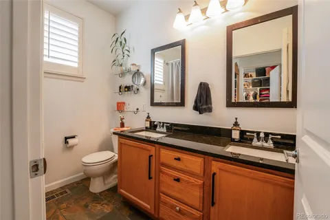 a bathroom with a granite countertop sink mirror vanity and toilet