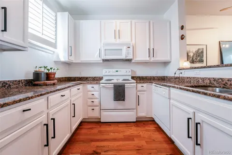 a kitchen with granite countertop white cabinets and white appliances